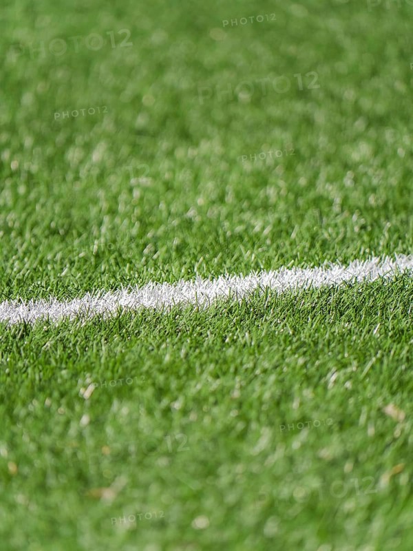 A close up image of a lush green grass soccer field featuring a white boundary line. The vibrant texture and clear marking highlight athletic grounds like soccer or football fields