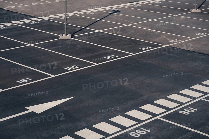 A clear view of numerous empty parking spaces with white numeric markings, located in Valdebebas, Madrid, indicative of its functionality as a transport hub servicing the metro, underground, suburban trains, and buses