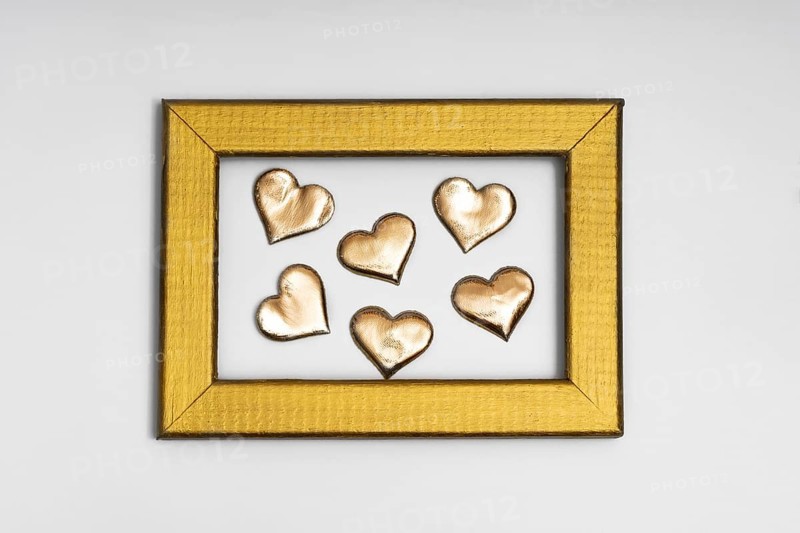 A collection of golden heart shapes arranged inside a textured gold frame, evoking themes of love and romance, perfect for St. Valentine's Day and wedding decorations