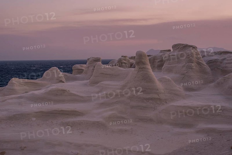 Serene evening view of the distinctive white rock formations at Sarakiniko Beach on the island of Milos, Greece, under a pastel sky