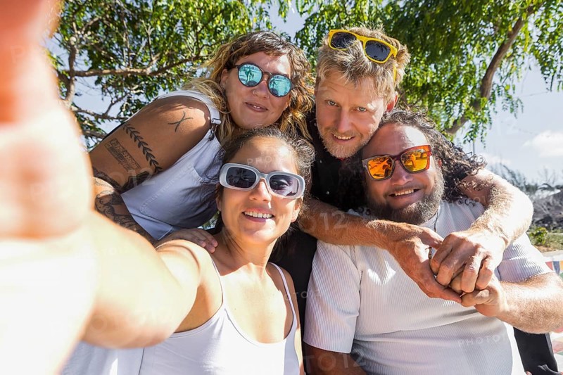 A cheerful group of LGBTQIA+ couples enjoying a sunny day outdoors. Their happy expressions and close poses convey unity, pride, and love in a natural setting