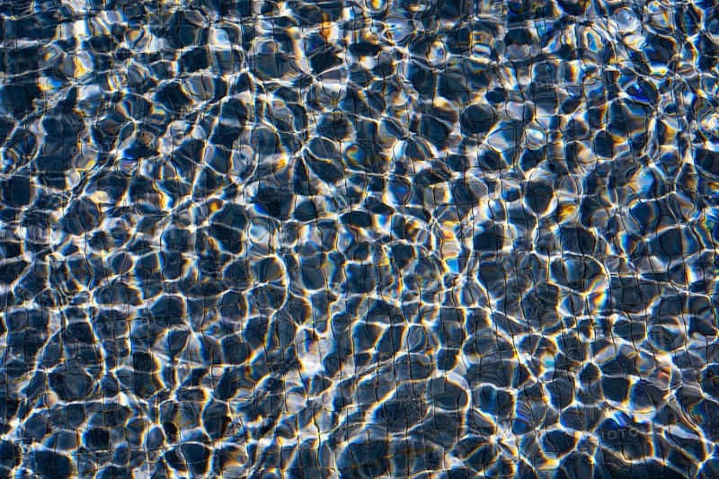 Sunlight dances on the rippling waters of Playa Blanca Port, Lanzarote, creating a mesmerizing pattern of light and shadow
