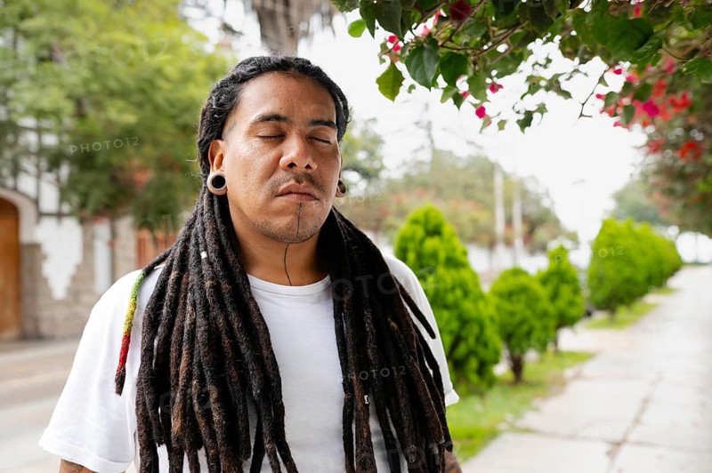A man with long dreadlocks stands peacefully with his eyes closed under blooming bougainvillea Located in the charming streets of Barranco, Lima, Peru