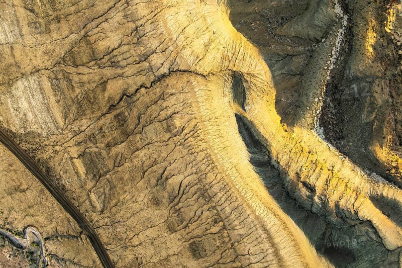 Aerial view of unique golden sandstone patterns in Utah's desert. Rugged terrain, sunlit textures, and geological features create a captivating natural landscape