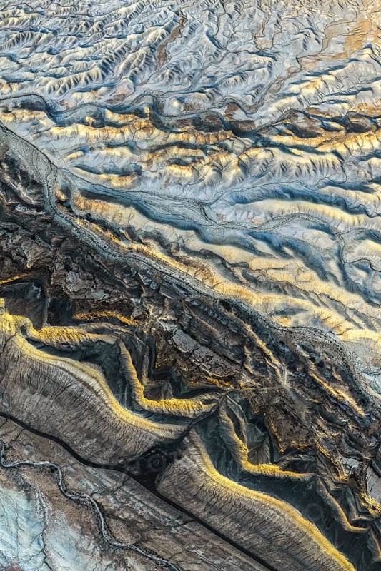 Aerial photograph showcasing the intricate golden sandstone formations of the Utah desert. The texture and patterns reveal the natural beauty and geological history