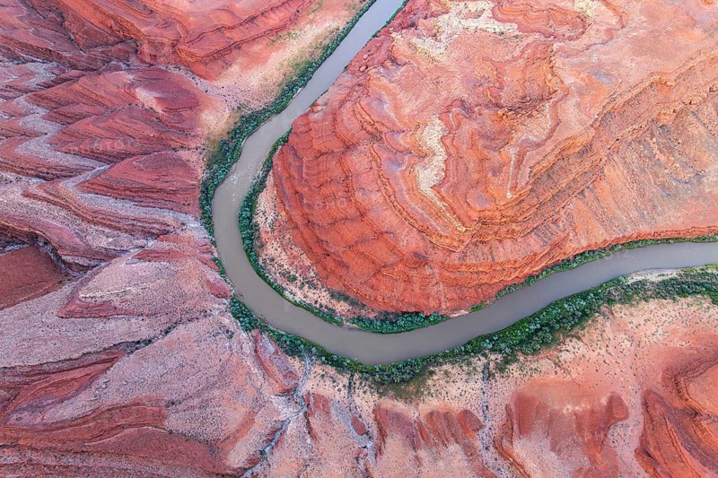Aerial photograph of Rio San Juan meandering through the vibrant red rock formations and greenery in Utah, USA, showcasing nature's artistry