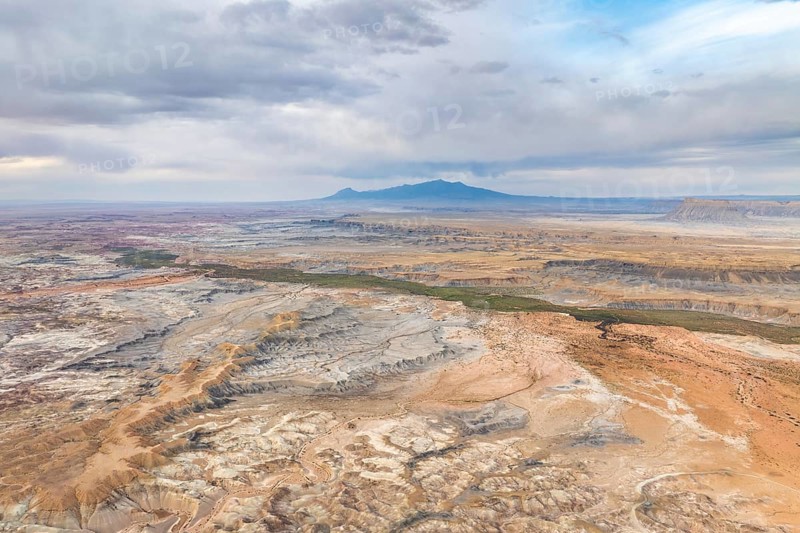 A stunning aerial drone view capturing the vast, rugged landscape of Hanksville, Utah, highlighting the unique geological features and vast expanses under a hazy sky