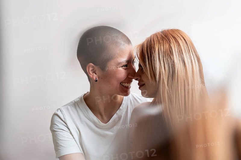 A tender moment captured between a joyful lesbian couple, sharing a loving embrace. Their intimacy and happiness are reflected in their warm smiles and gently touching foreheads