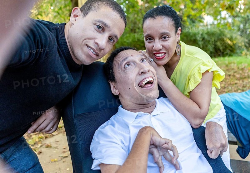 Spanish Cameroonian siblings enjoying a moment outdoors. The family shares a joyful connection, with one sibling having cerebral palsy, illustrating unity and love