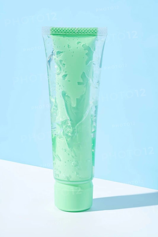 Transparent green tube filled with aloe vera infused cosmetic gel showcased against a light blue background, highlighting its soothing and hydrating properties