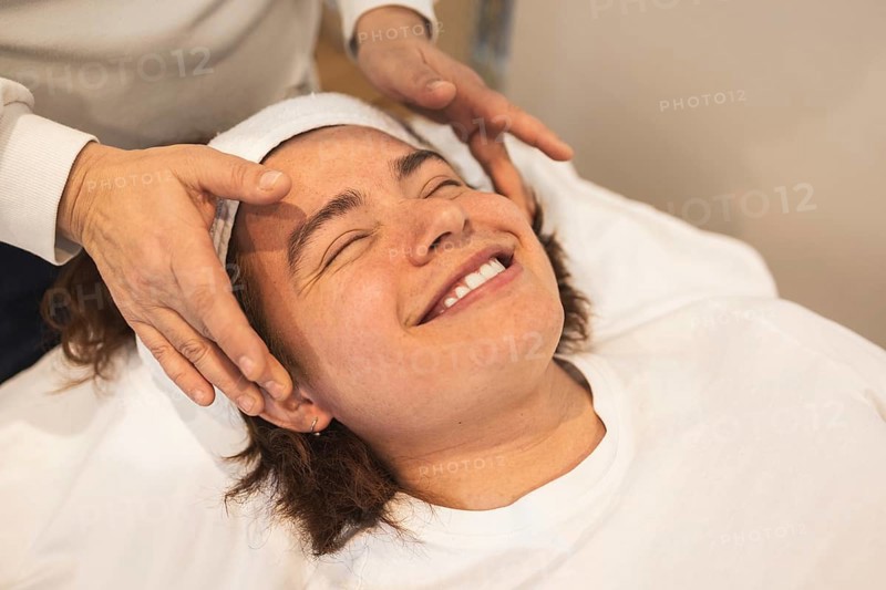A man enjoys a relaxing facial massage using organic products The atmosphere is serene, promoting wellness and self-care The man wears a headband while lying on a massage table