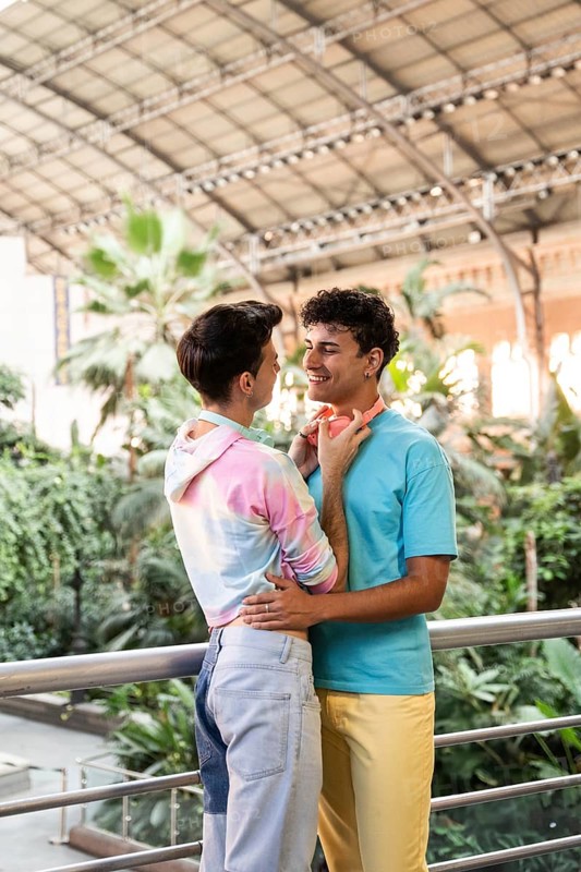 A cheerful gay couple embracing in a lush indoor garden. Their colorful outfits and vibrant surroundings highlight a joyful celebration of love and togetherness