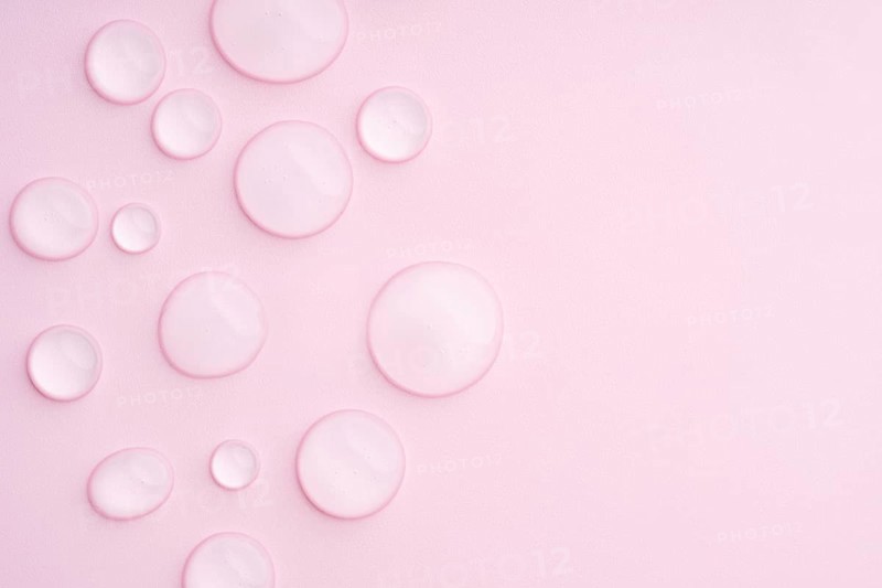 This image displays a pastel pink background with clear droplets, creating a serene and calming visual texture Ideal for beauty, skincare, or relaxation-themed projects