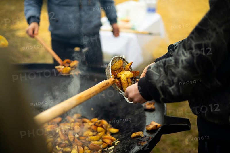 Cropped unrecognizable staff cooking potatoes at a bustling street food fair, enhancing the aroma with smoky flavors, creating an enticing atmosphere for fair-goers who enjoy outdoor culinary experiences