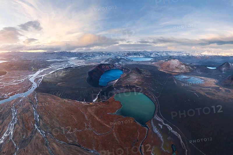 Captivating aerial view of Iceland's Highlands showcasing volcanic craters, vivid blue lakes, and rugged terrain under a dramatic sky, highlighting geological diversity