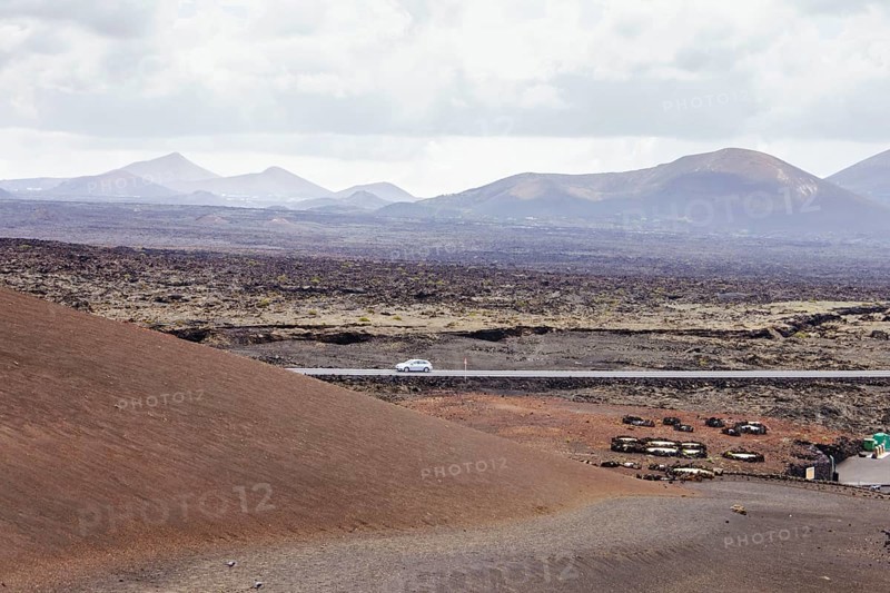 Deserted road in a volcanic landscape. The arid terrain and mountains on the horizon highlight the natural beauty of the scene