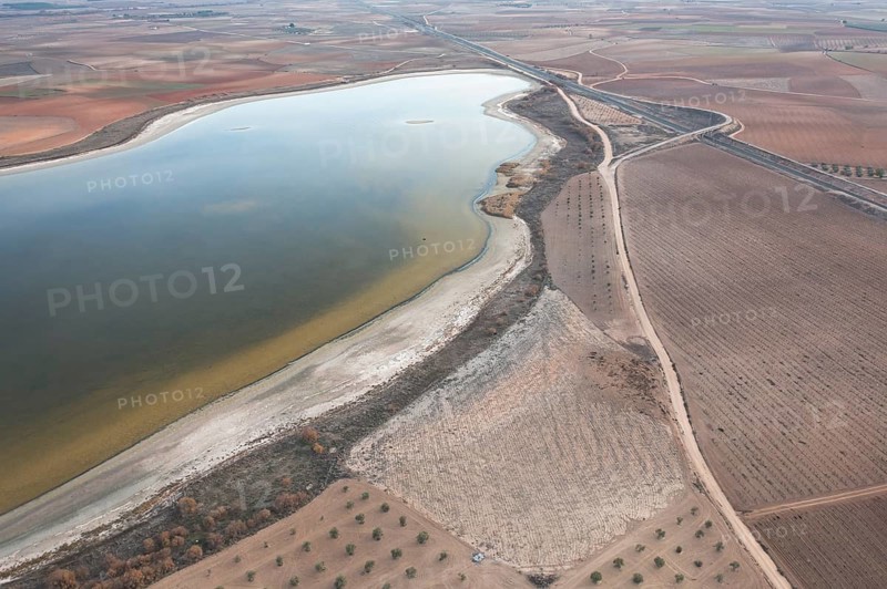 Aerial view of Toledo Lagoons, Spain, showcasing a serene lake amidst farmland. Home to diverse bird species like Common Crane, Mallard, and Greater Flamingo