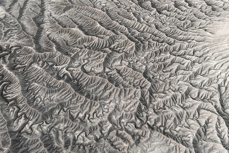 Stark aerial image showcasing the intricate, textured landforms of Caineville Mesa near Hanksville, Utah, highlighting the unique geological patterns
