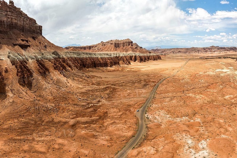 Scenic aerial capture of the unique, eroded rock formations and sprawling terrain at Goblin Valley State Park in Utah, USA, showcasing nature's artwork and winding road cutting through the desert