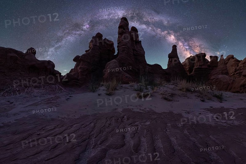 A mesmerizing night sky arches over unique sandstone formations in Goblin Valley State Park, Utah. The vibrant Milky Way complements the landscape's rugged beauty