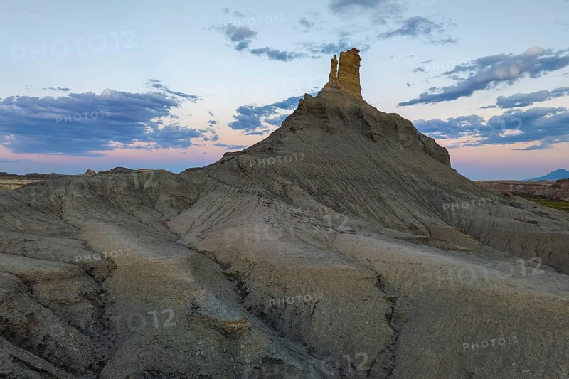 Majestic views of a unique rock formation against a vibrant sunset in Utah, capturing the serene yet rugged natural beauty of the area