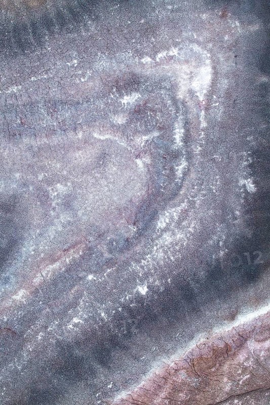 Aerial shot of a sandstone lake showcases soft pastel shades and organic textures, creating a dreamlike abstract pattern reminiscent of a watercolor painting, highlighting nature artistry