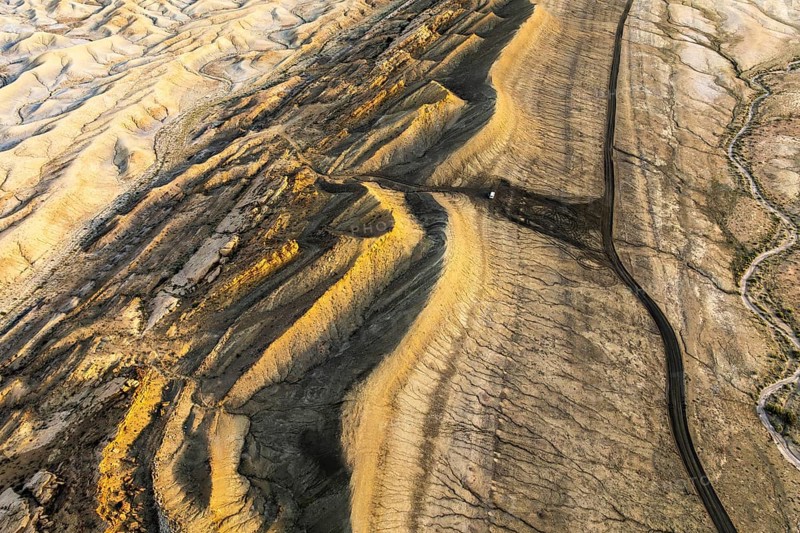 Captivating aerial shot showcasing the golden hues of sandstone formations in Utah's desert. The unique geological patterns create a mesmerizing and serene landscape