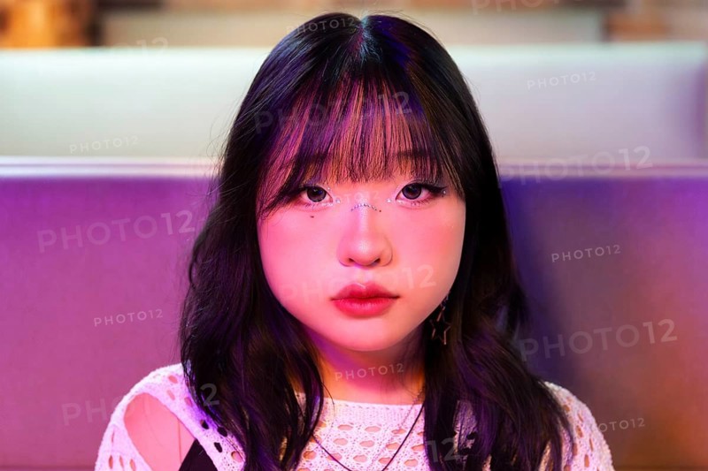 An Asian Gen Z girl is immersed in the vibrant atmosphere of an arcade Her expression reflects the excitement and energy of the colorful gaming environment