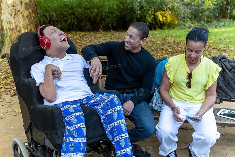 A Spanish Cameroonian family enjoying time outdoors. One sibling with cerebral palsy is engaged with others, highlighting Mixed-race unity and joy