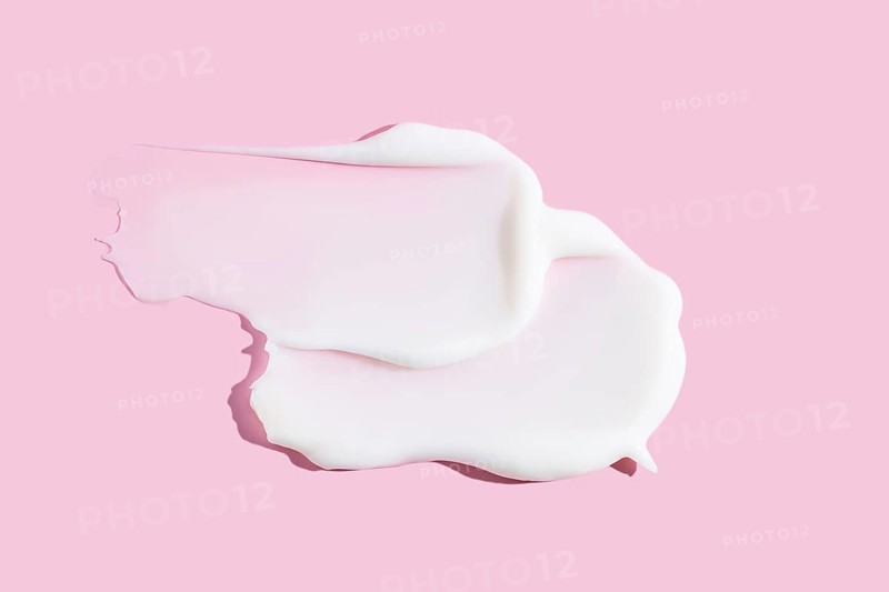A delicate smear of creamy cosmetic product, displaying texture against a soothing pink background. Ideal for beauty and skincare themes