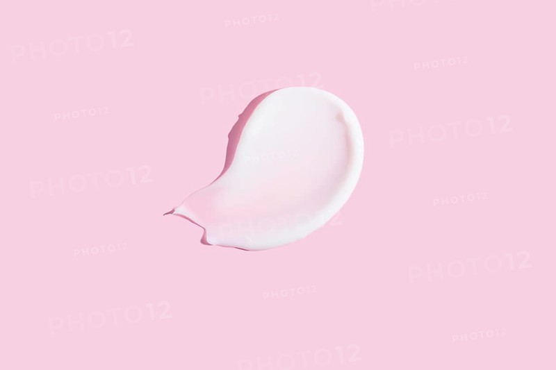 A high-quality image featuring a dollop of cosmetic cream smeared on a pastel pink background, ideal for beauty and skincare themes