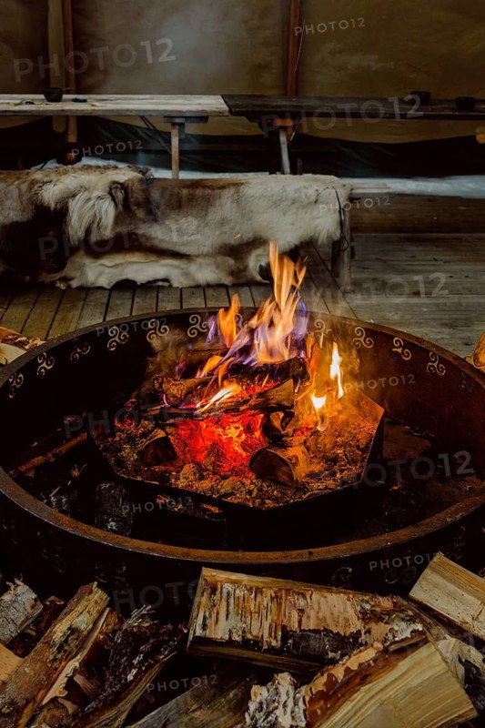 Warm and inviting fire in a Scandinavian setting in Swedish Lapland. Wooden logs are ready for burning, creating a cozy atmosphere
