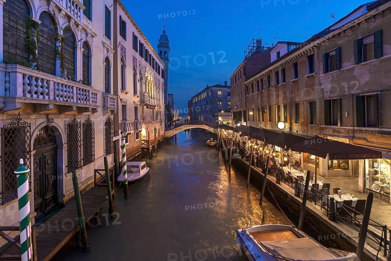 Dinner with restaurant on the canal, in the back the tower of the church of Santa Maria della Pietà, Venice, Veneto. italy