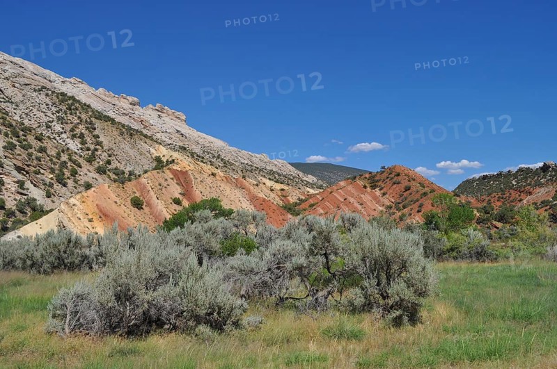 Rocks with colorful soil, vegetation and blue sky in hilly landscape, Dinosaur National Monument, Utah, USA