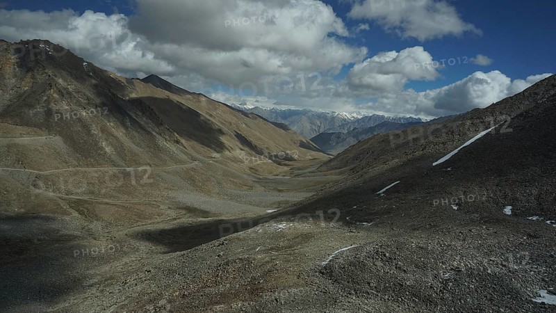 Wide, barren valley with mountains and clouds on the horizon, trekking in Ladakh, Stok la, Himalayas, India
