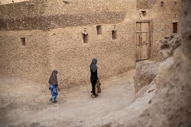 Siwa, Egypt. March 11th 2018 A woman and child walk through the traditional mud brick buildings of Siwa Oases
