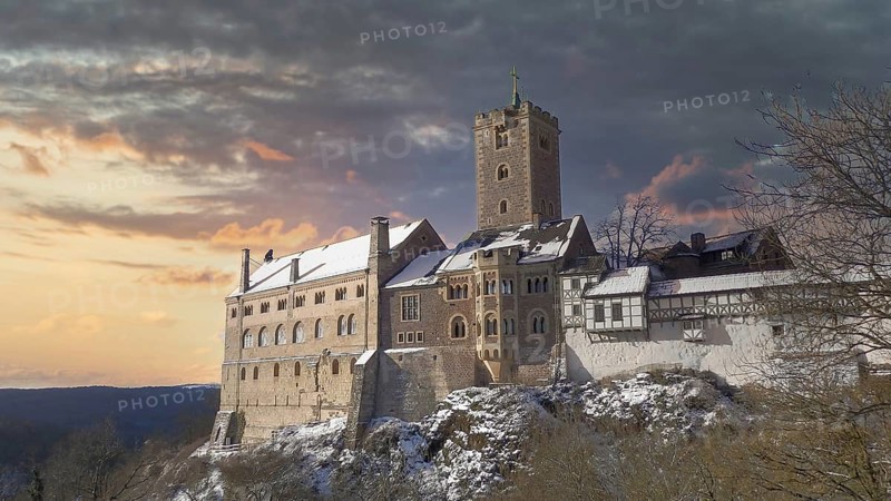 Snowy Wartburg in Eisenach in front of a picturesque and dramatic sky in romantic colors, at dusk, hiking on the Rennsteig, Thuringian Forest nature park Park