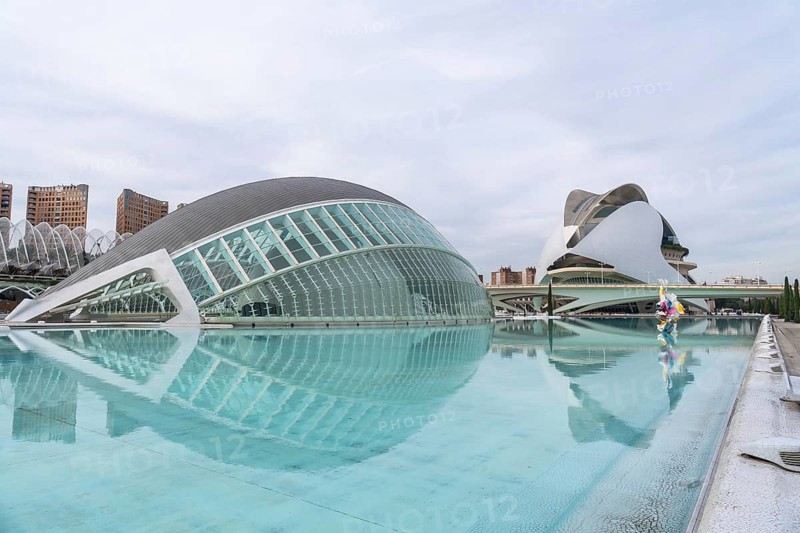 City of arts and sciences in valencia featuring futuristic l'hemisferic and palau de les arts reina sofia reflected in calm pools, sleek glass and steel architecture under a cloudy sky