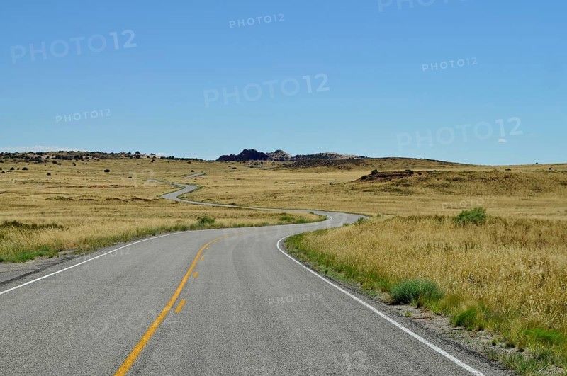 Endless road snakes through a dry desert landscape under a clear blue sky, Canyonlands National Park, Island in the Sky, Utah, USA
