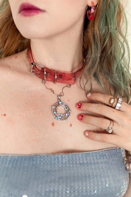 A stylish woman with a pink choker, rings, and earrings Her colorful hair complements the artistic accessories, showcasing an edgy, modern fashion statement Close-up shot