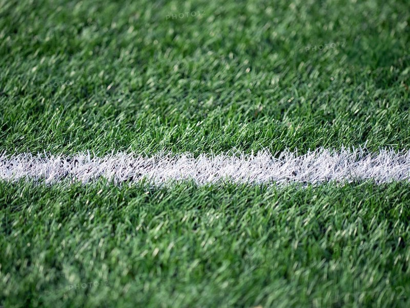 Detailed shot of a soccer field, highlighting the contrast between the vibrant green grass and a crisp white line. Perfect for themes of sports, leisure, and outdoor activities