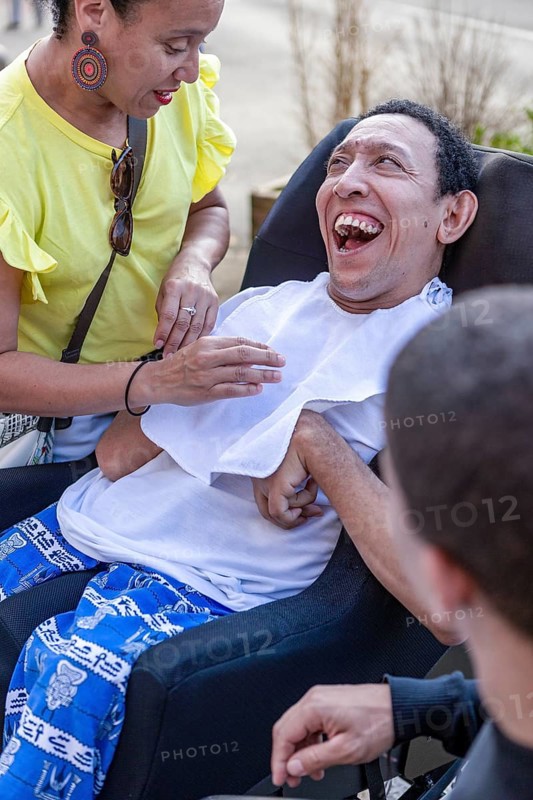 A Spanish Cameroonian family of siblings enjoying a moment together, with one sibling having cerebral palsy. The image captures warmth and Mixed-race diversity