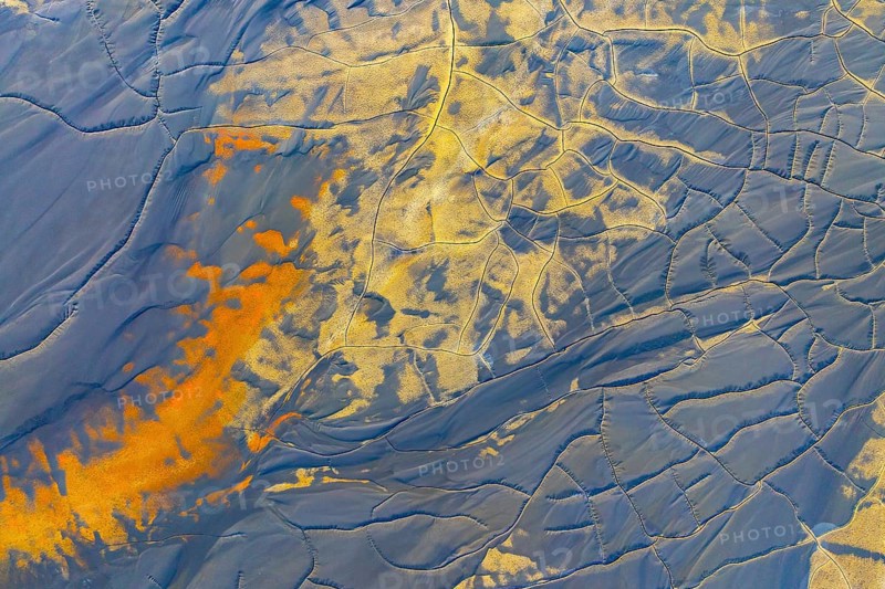 Aerial view of multicolor mud formations showcasing vibrant patterns and textures Shades of orange and blue blend artistically with intricate natural lines and shapes