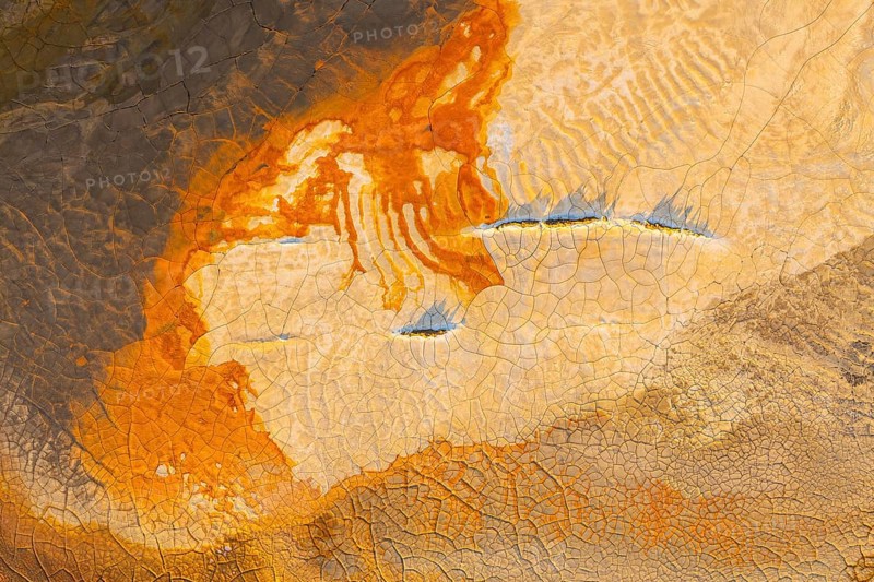 Aerial view of vibrant multicolor mud patterns showcasing orange, brown, and earthy hues The crackled textures create an abstract landscape, highlighting nature's artistry