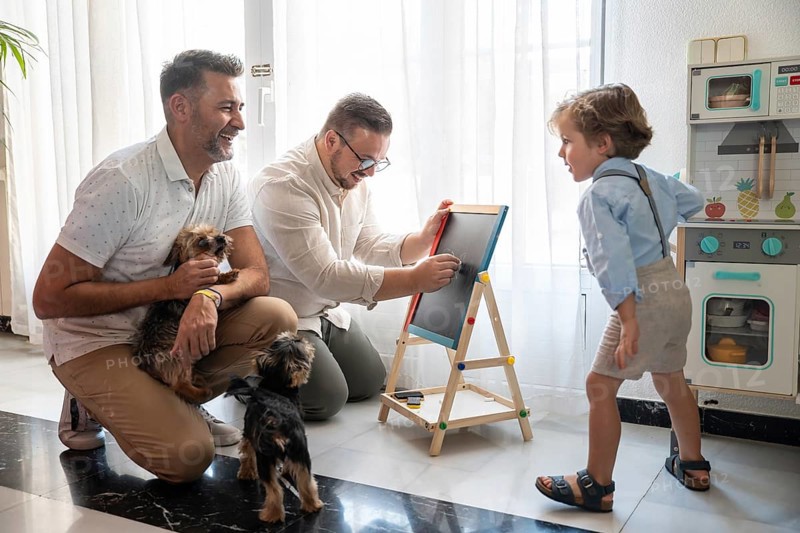 A joyful moment with a gay couple and their son, surrounded by joyful pets, sharing laughter and creativity at home. The scene radiates love and happiness