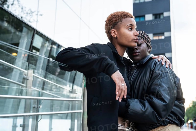 A loving LGBT multiethnic couple embraces outdoors in an urban environment. The moment captures intimacy and connection, reflecting beauty in genuine affection and love