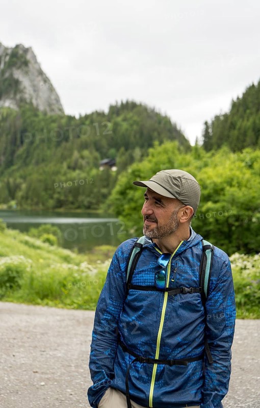 A man in outdoor gear enjoys the serene landscape at Lac de Taney, Switzerland Surrounded by lush greenery and mountain peaks, it's a perfect scene for nature lovers