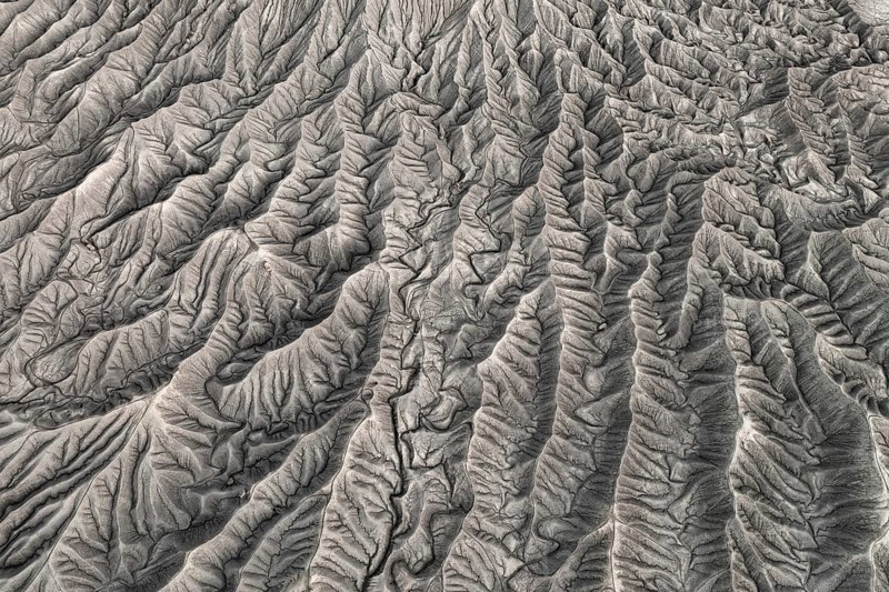 Stunning aerial photograph capturing the intricate, wavy patterns of the eroded land formations at Caineville Mesa near Hanksville, Utah, showcasing nature's artistry in geomorphology
