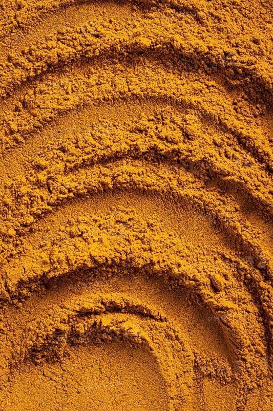 A vibrant close-up of golden curry powder, showcasing its textured surface with swirling patterns This aromatic spice is perfect as an ingredient for cauliflower curry soup and more