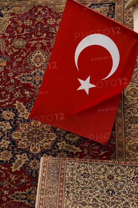 Istanbul, Turkey, February 23rd 2018. A Turkish flag and antique carpet for sale in a shop in the Grand Bazaar, Istanbul, Turkey